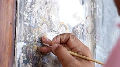 一位绘画艺术家的手在修理一幅中国画。 旧建筑墙体国画改造..